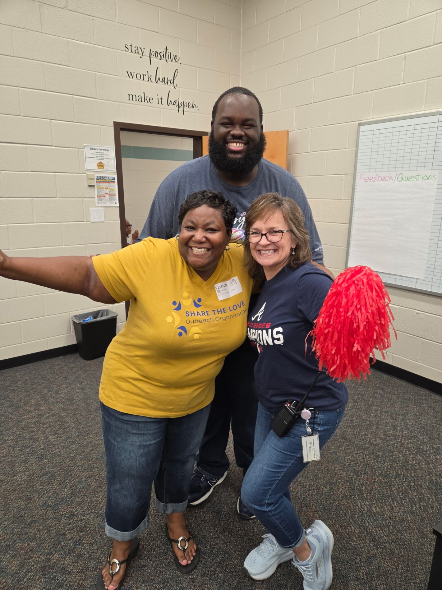 Volunteers and school staff celebrating with a pom-pom at the Sanders Elementary pizza party