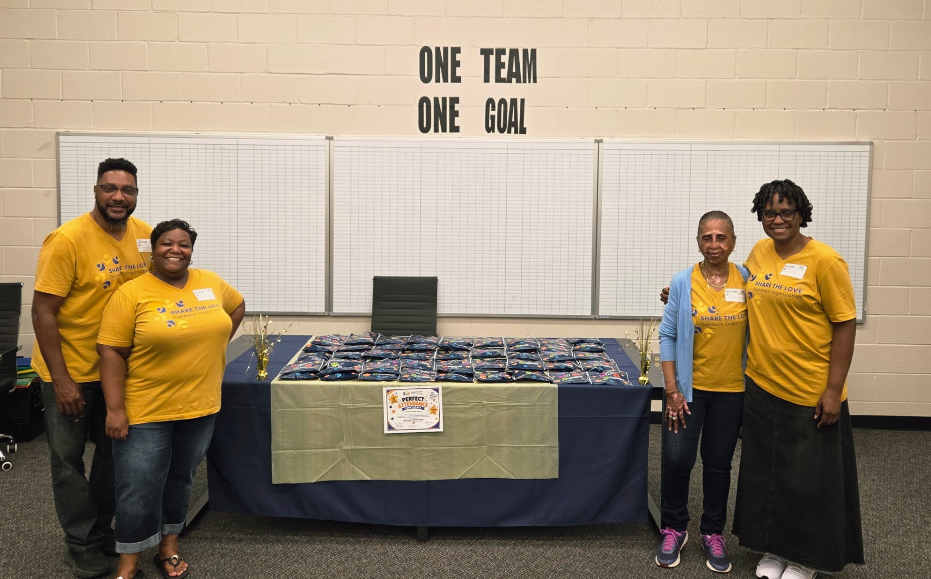 Share the Love volunteers and Sanders Elementary staff celebrating the perfect attendance pizza party together