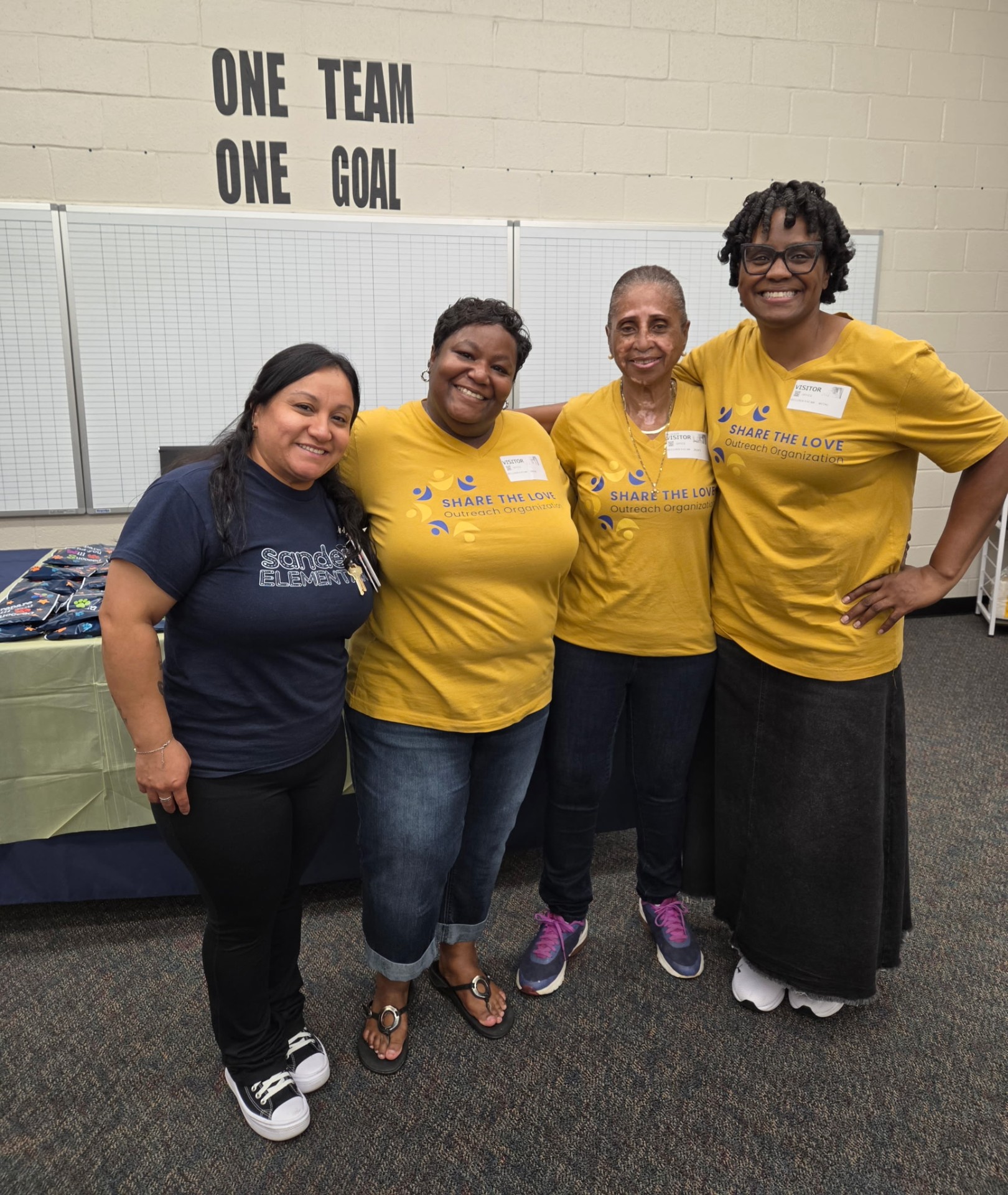 Share the Love volunteers and Sanders Elementary staff pose together for the perfect attendance pizza party