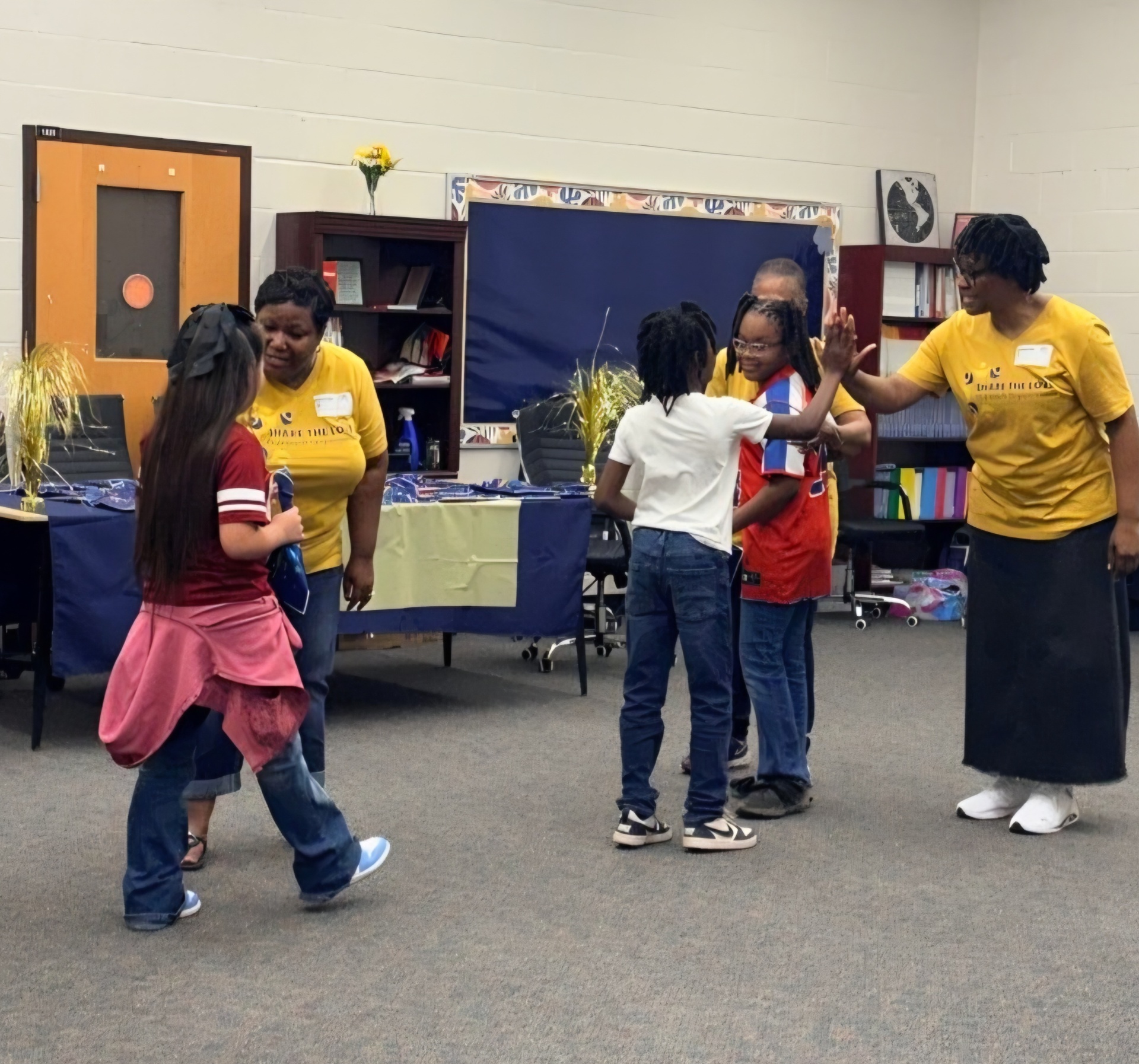 Share the Love volunteers giving high-fives to Sanders Elementary students at the perfect attendance celebration