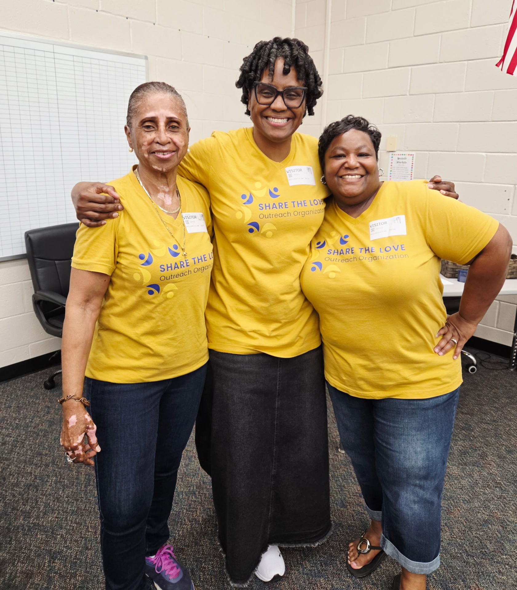 Share the Love volunteers in matching yellow shirts celebrating together at Sanders Elementary
